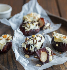 Homemade date candies with nuts, covered with white chocolate and decorated with chopped nuts.