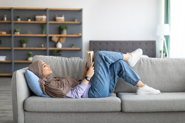 Muslim woman having rest at home, reading book