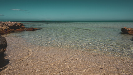 Close up of woman feet walking barefoot on sand beach in sea water. Vacation, travel and freedom concept. People relaxing in summer.