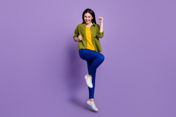 Full body photo of young girl happy positive smile rejoice victory lucky fists hands jump isolated over violet color background