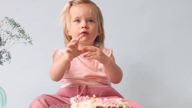 little beautiful blue-eyed girl celebrates her first birthday in the style smash a cake and she tastes her first birthday cake