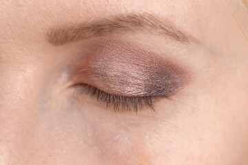 Make-up of the eyes of a young woman in brown and pink tones close-up. Next stage