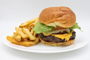 Perfect American Style Cheeseburger with a Fried Egg and Lettuce and Tomatoes on a White Plate with French Fries