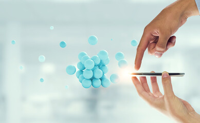 Businessman hands holding a smartphone with a bunch of spheres levitating above. Mixed media