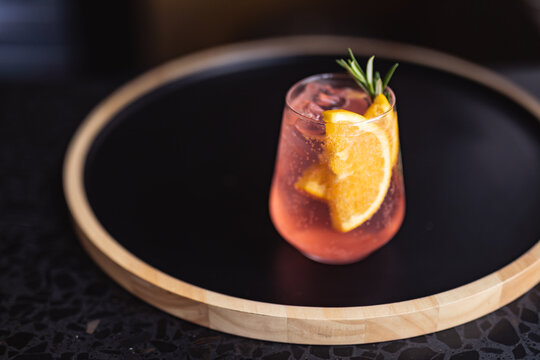 Close up view of gin cocktail with fresh lime and rosemary on wooden tray