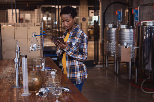 African american female worker using digital tablet at gin distillery