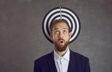 Unlucky businessman caught in dangerous trap. Studio portrait of man whose head serves as dartboard...