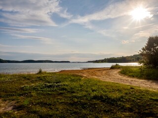 Douglas Lake in the spring in Tennessee with the Great Smoky Mountains in the background, the water and sandy shore with a blue sky filled with clouds in the distance.