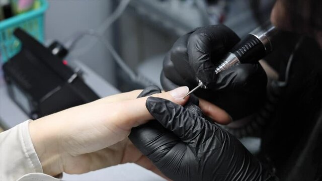 the process of hardware manicure in the salon, removing gel polish or acrylic from long nails with the help of a manicure machine