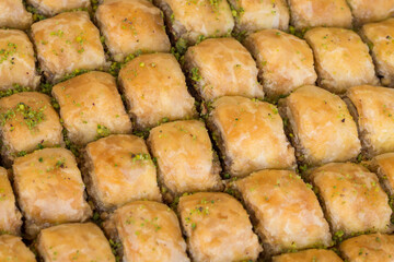 Full frame of rectangle-shaped nut baklava on a tray with pistachio toppings
