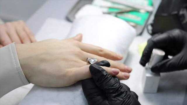 the process of manicure in the salon on long nails, cutting the cuticle with a special tool
