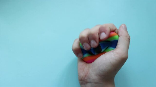 colorful trendy antistress sensory fidget push toy Snapperz in kid's hands on blue background
