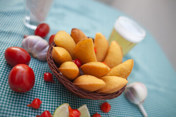 pastel de angu com tomates cereja alho e cerveja em mesa de bar