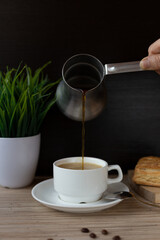 a hand pouring coffee into a mug