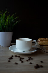 a cup of coffee on a wooden table with pastries and a potted plant