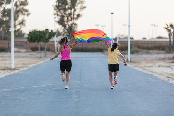 Girls running with LGBT flag. LGBT and lesbian couple concept. Horizontal