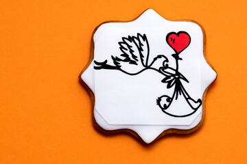 stork caring a child, with a red heart, on orange background 