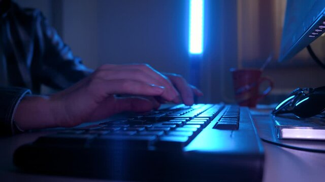 Male hands are typing on the keyboard at night. The blue lantern is shining. Night work concept. neon style