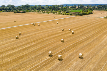 A bird's eye view of a harvested field of grain with straw bales 