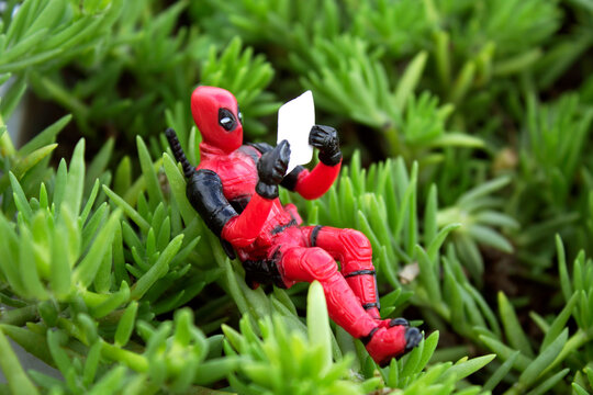 Rio de Janeiro, Brazil, November 25, 2018:  Deadpool Minifigure sitting on plant. Deadpool reading a newspaper under the plant.