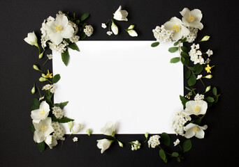 Floral frame made of different spring flowers on black background. Flowers flat lay. Space for text
