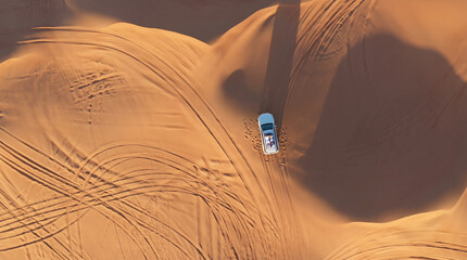 AERIAL. Top view of young couple relaxing on the car's roof at the desert.