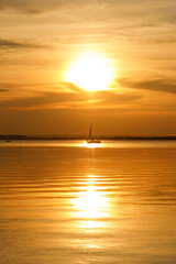 Naklejka na ściany i meble Yacht sailing against sunset. Black silhouette of sailboat.