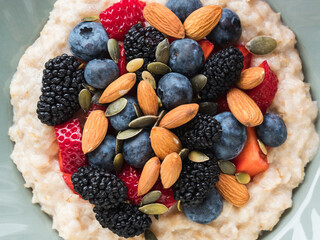 Delicious breakfast oat porridge on plant milk with nuts and berries on marble table