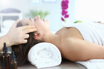 Obraz na płótnie Canvas Young woman doing head massage in spa center