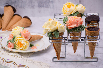 Beautiful piped buttercream flowers in cone cupcakes on stylish table