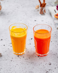 Side view on glass of fresh orange and carrot juice on a light background