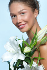 Portrait of a beautiful young woman with clean skin, soft day makeup and white lilies flowers,...