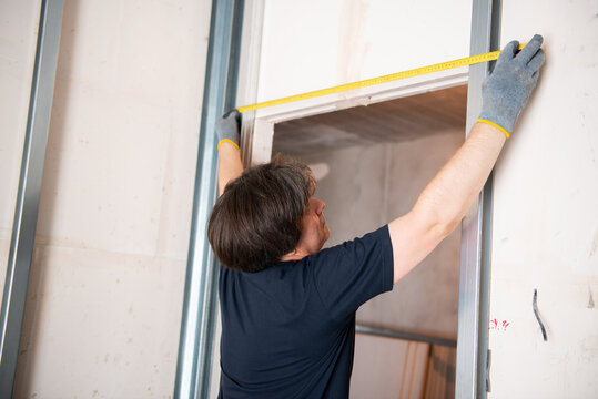 Male worker attaches profile for drywall for room soundproofing. Construction work, repair. Renovation
