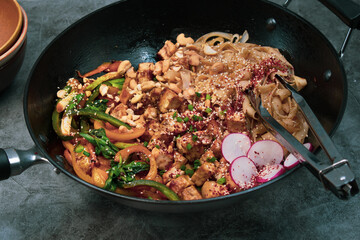 Vegan stirfry with tofu peppers and rice noodles in wok