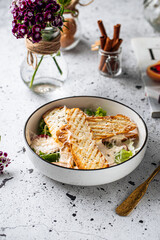 Bowl of fresh chicken caesar salad on light decorated background