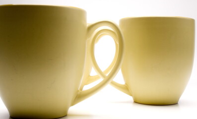 Three coffee mugs lined up with their handles pointed inward, viewing straight down the hole made by the handles.