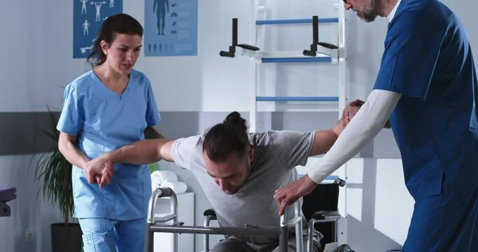 Handicapped man trying to stroll with walking frame near doctors