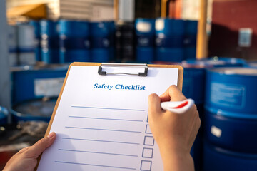 A safety checkilist which is clipped on wooden clipboard with blurred of worker hand using pen to...