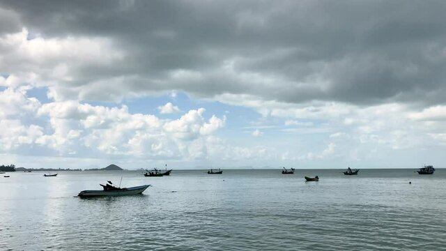 fishing boats on sea in Dark clouds in soft blue sky. dramatic rainstorm cloud above the sea with small speet boats in rainy wet weather. gray cloudscape nature background. traveling in rainy season.