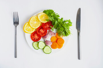 Summer menu, a plate of vegetables, a fork and a knife on a white background, flat lay