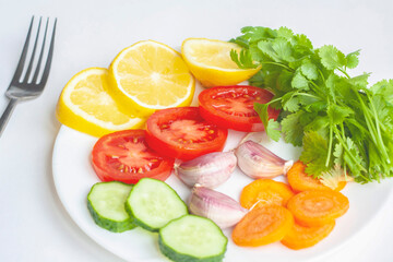 Summer menu, a plate of fresh vegetables and a fork on a white background