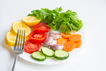 Summer menu, a plate of vegetables and a fork on a white background