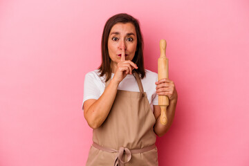 Fototapeta premium Middle age pastry chef woman isolated on pink background keeping a secret or asking for silence.