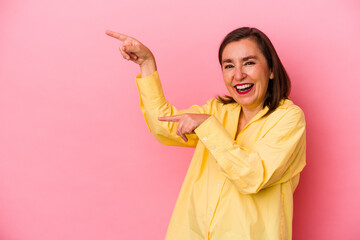 Middle age caucasian woman isolated on pink background excited pointing with forefingers away.
