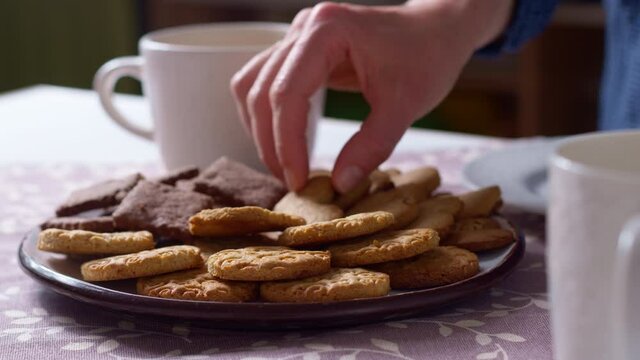 People's hands take cookies from a plate. 4K.