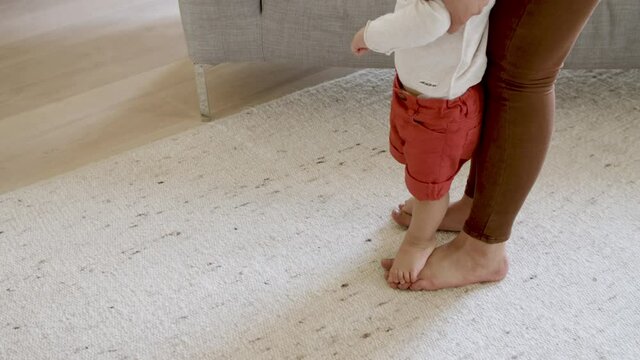 Close-up of mother and sons feet at home. Son putting her feet on mothers feet. First steps, parenthood concept. 