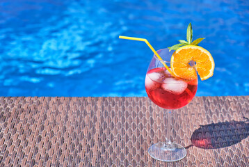 Cocktail with orange and ice in a swimming pool. Space for text