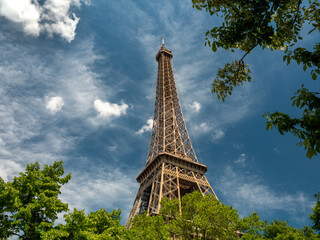 Paris, France, May 2021. Eiffel Tower from the bottom photo between the trees, sunny evening, bottom view, blue background, free space for text
