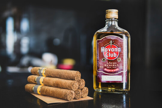 A bottle of Cuban Havana club rum and cohiba cigars on the table on a dark background.