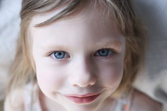 Portrait of smiling little girl with blue eyes in bed